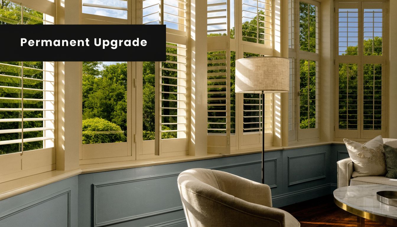 Elegant bay windows featuring white plantation shutters in a cozy, stylish living room with blue wainscoting.